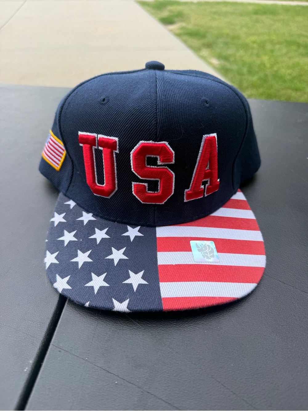 Navy blue snapback cap with red 'USA’ logo and American flag patch